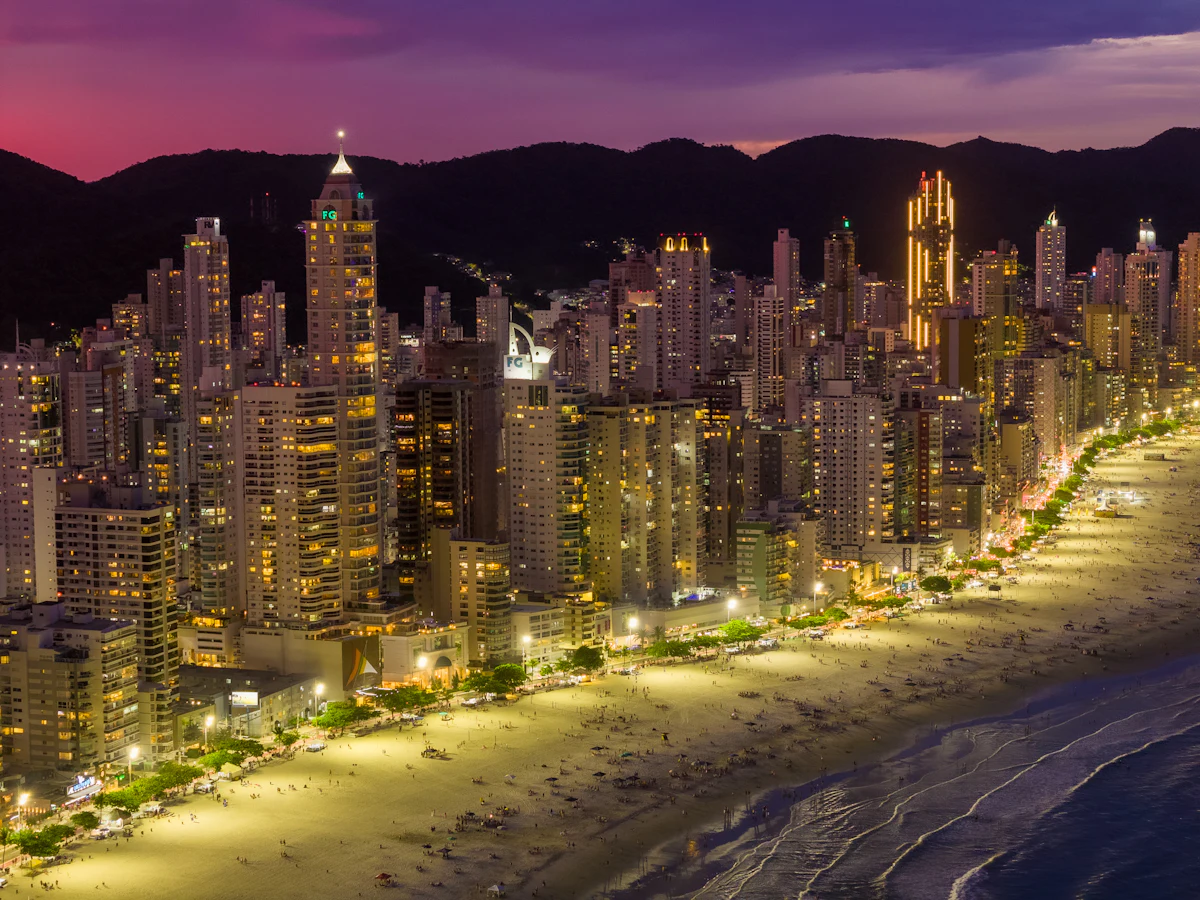 Vista aérea nocturna de Balneario Camboriú, con la costanera iluminada y los cerros detrás