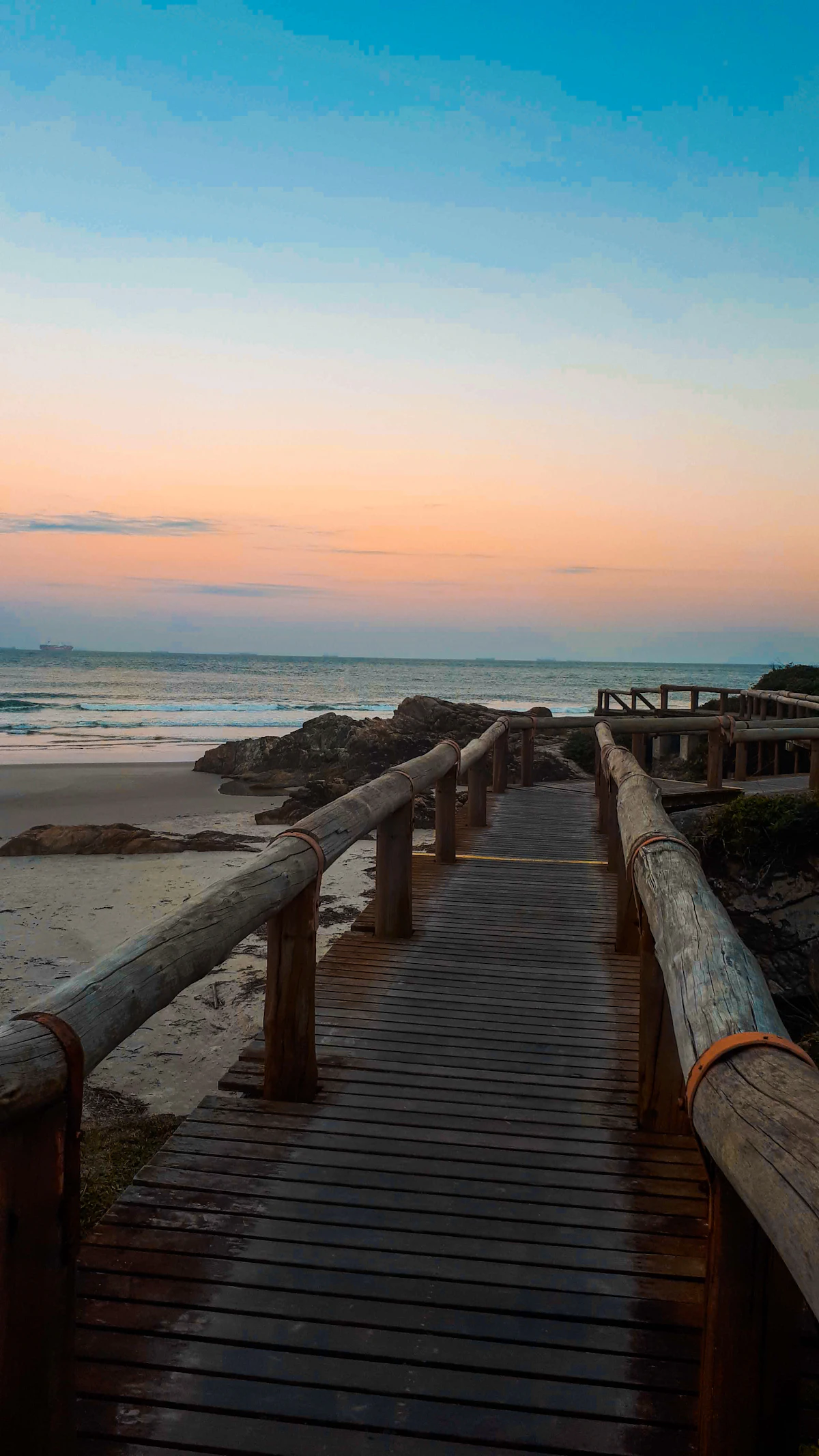 Pasarela de madera hacia la playa al atardecer en Ilha do Mel