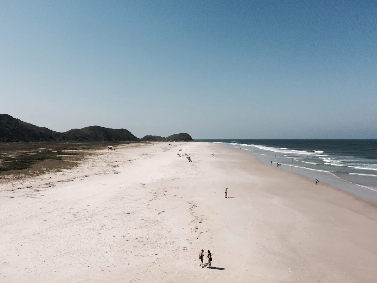 Playa larga de arena blanca con cerros al fondo en la costa de Paraná