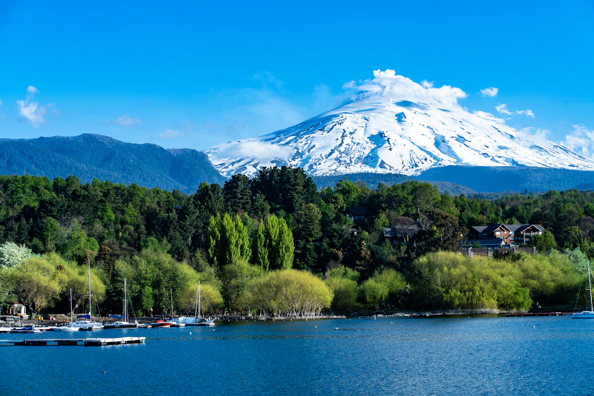 Volcán Villarrica nevado sobre el lago y los veleros de Pucón
