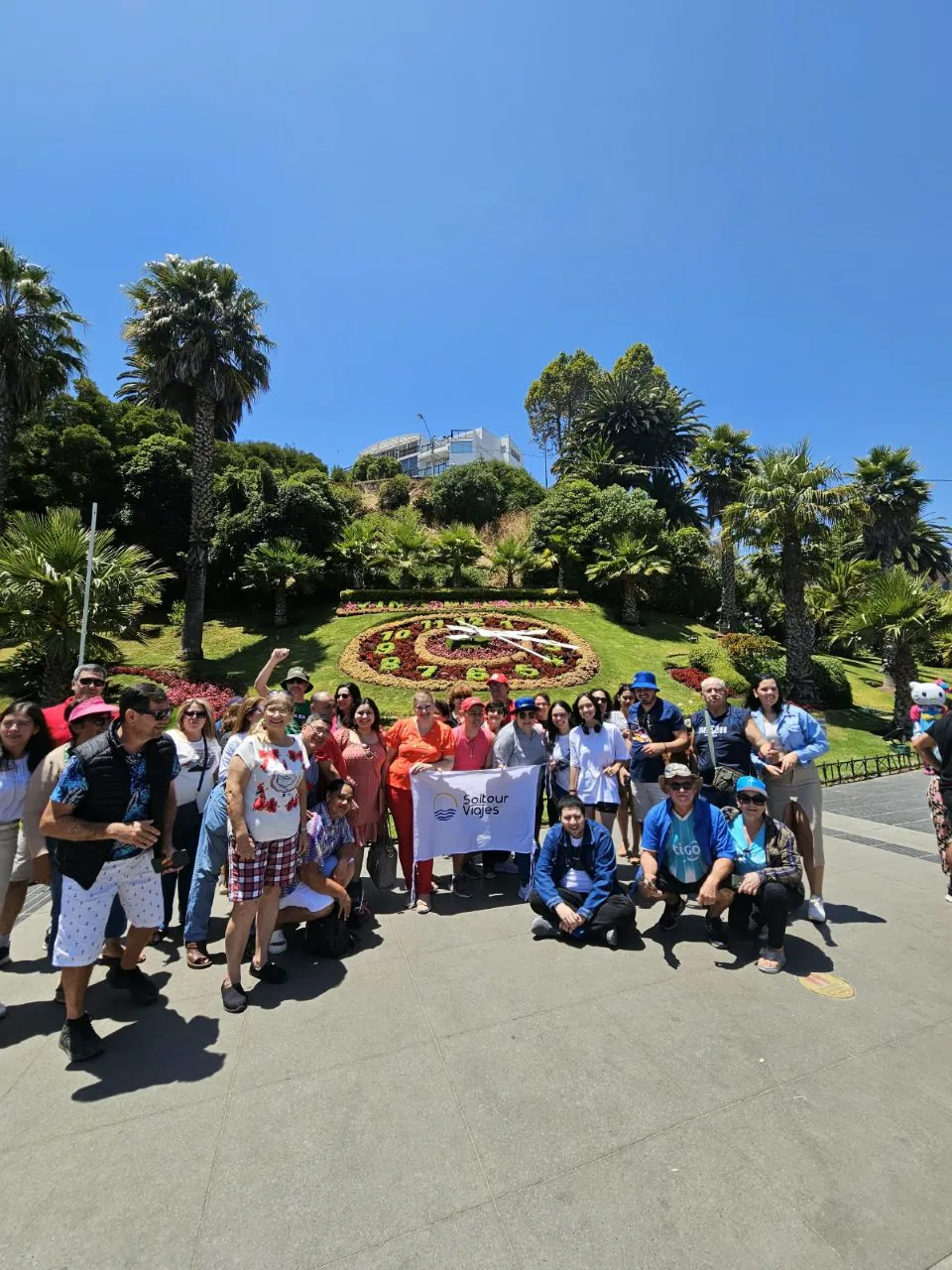 Grupo de viajeros de Soltour en un parque con un reloj de flores