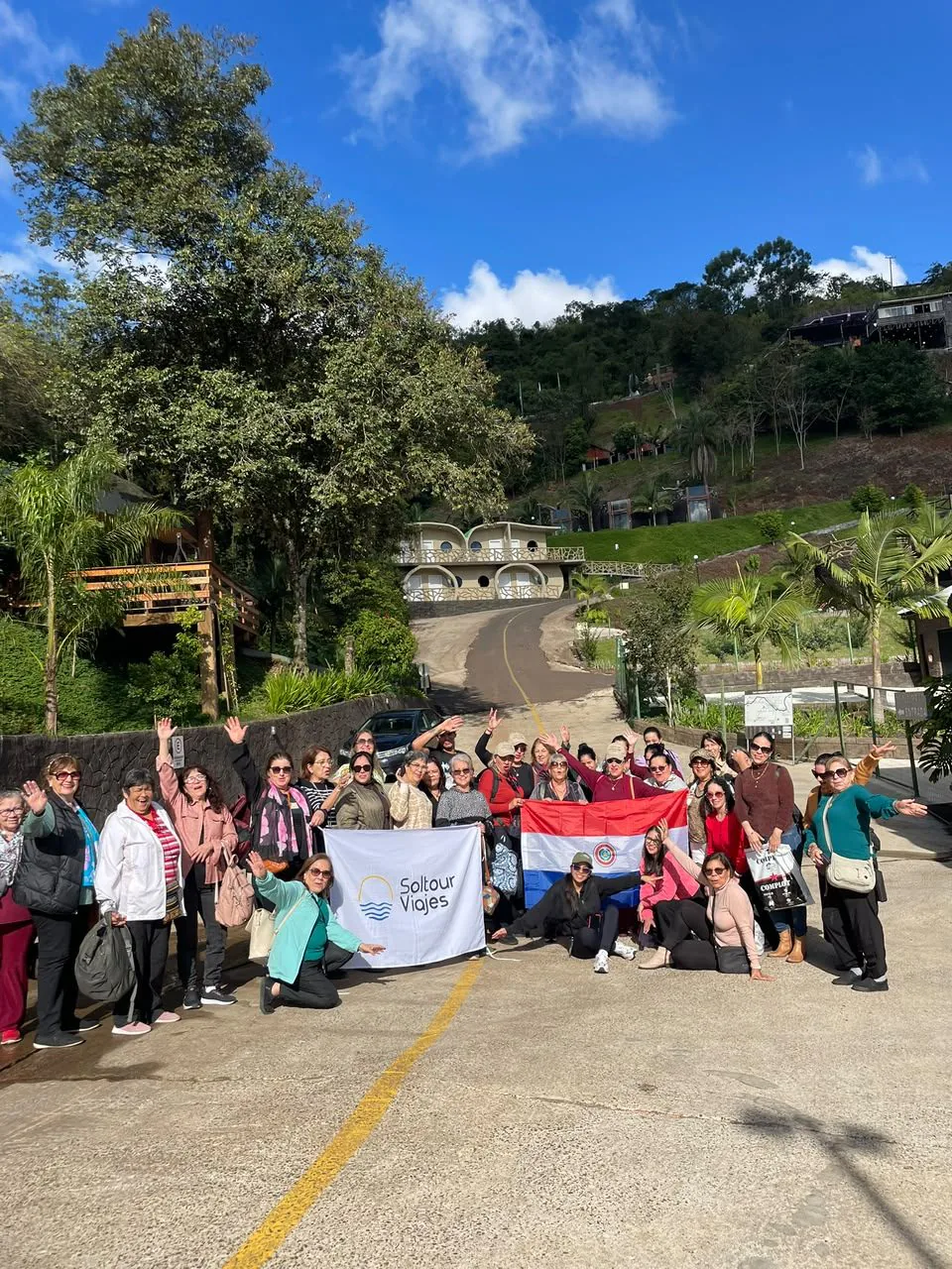 Grupo de viajeros de Soltour con la bandera paraguaya, entre árboles