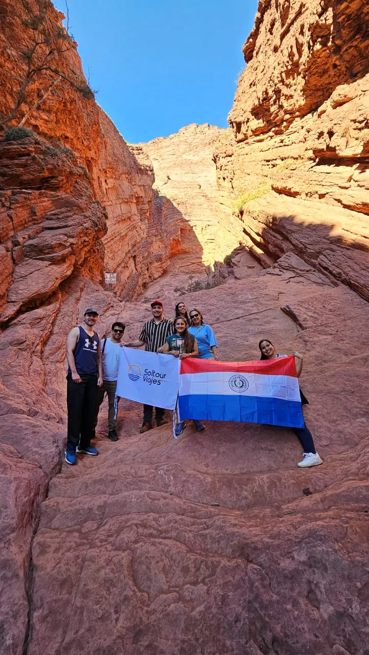 Viajeros de Soltour con las banderas de la agencia y de Paraguay, en un cañón de roca roja