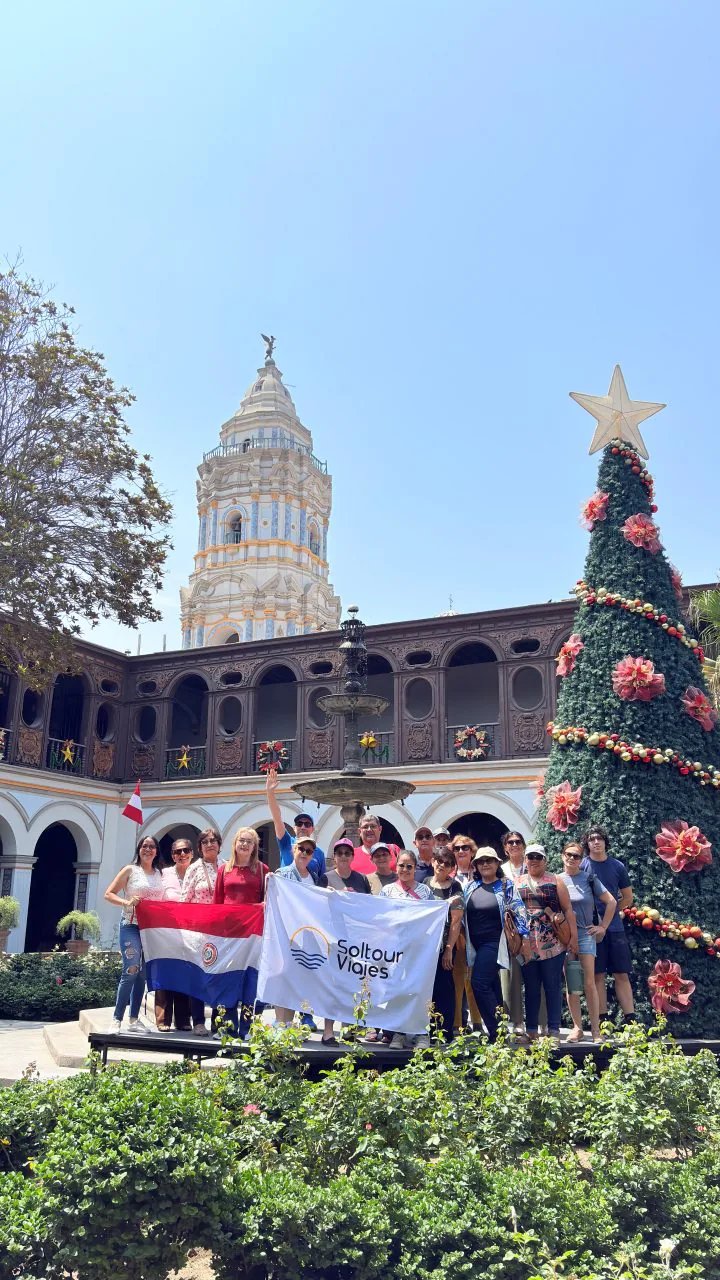 Grupo de viajeros de Soltour con las banderas de la agencia y de Paraguay, junto a un árbol de Navidad